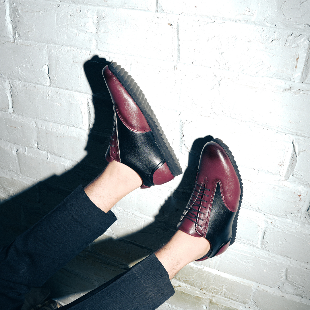 A fashionable Monkstory Dual Colour Smart Sneaker in burgundy and black leather that offers comfort.