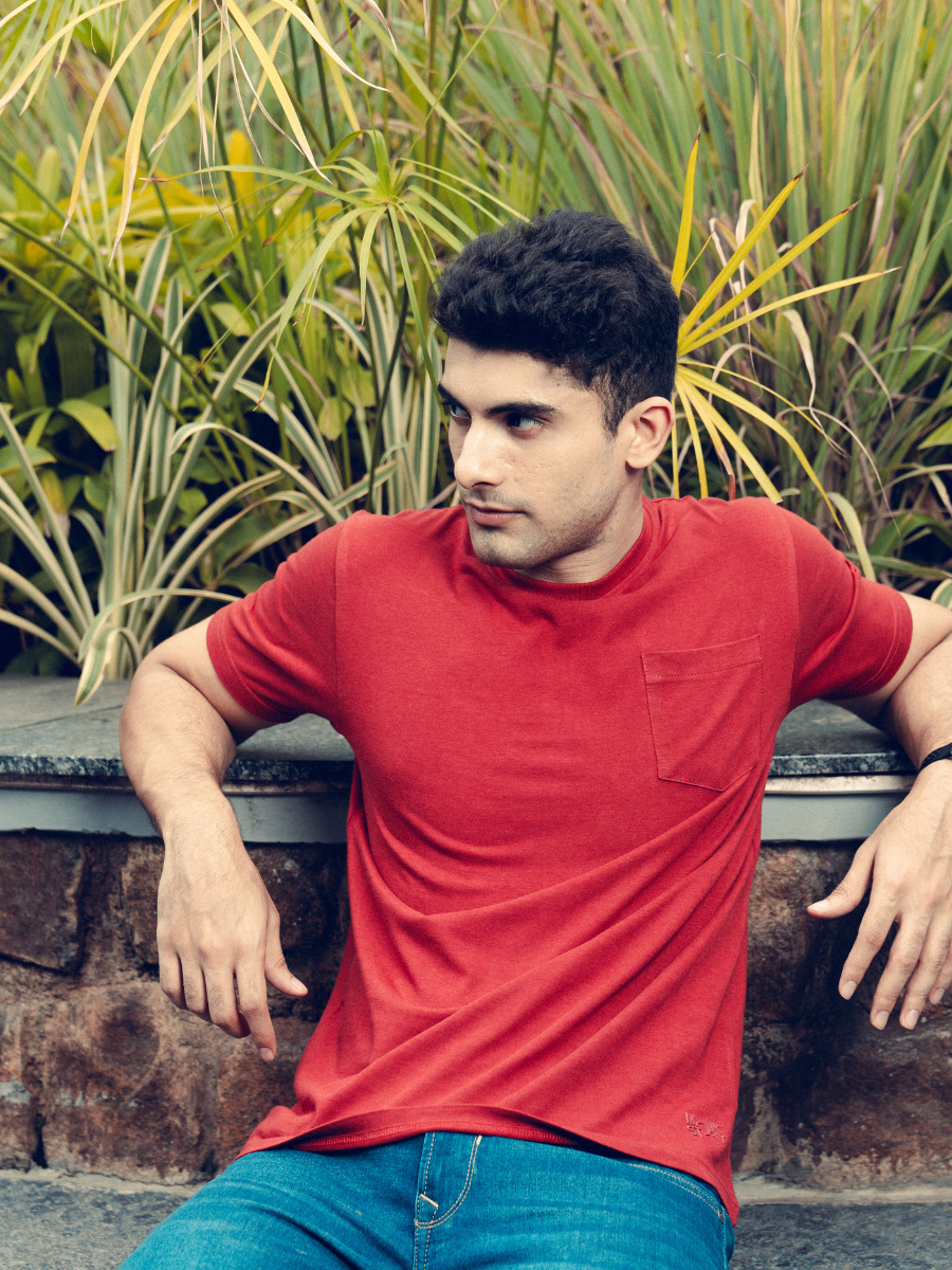 A young man in a Monkstory Bamboo Cotton Crew Tee - Terracotta Red is posing for a photo.