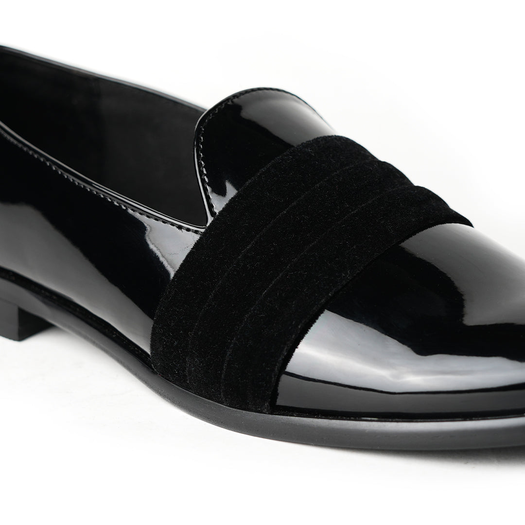 A black Tuxedo Slip-on with a patent leather finish and a bow on the side, by Monkstory.