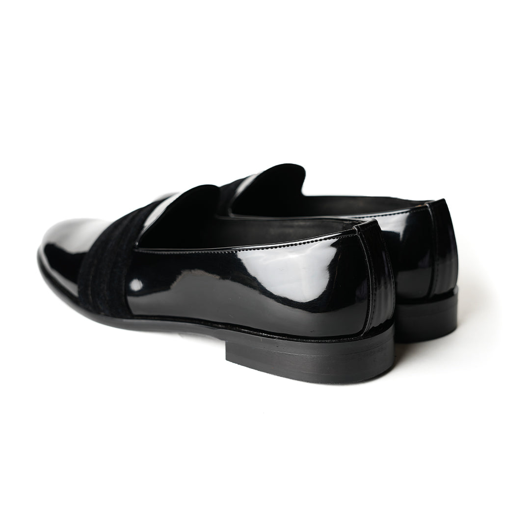 A black Tuxedo Slip-on with a patent leather finish and a bow on the side, by Monkstory.