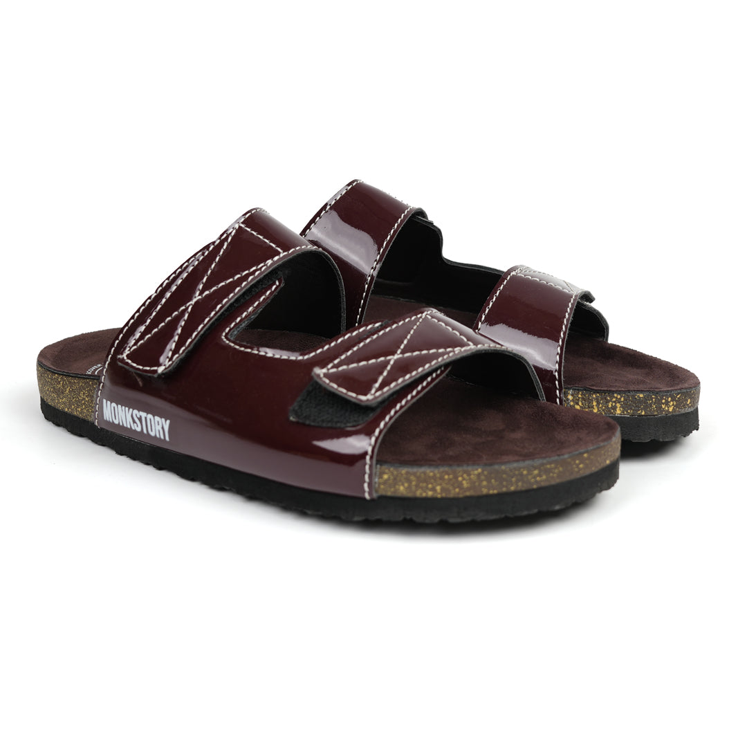 A pair of glossy brown Monkstory sandals with cork dual-straps on a white background.