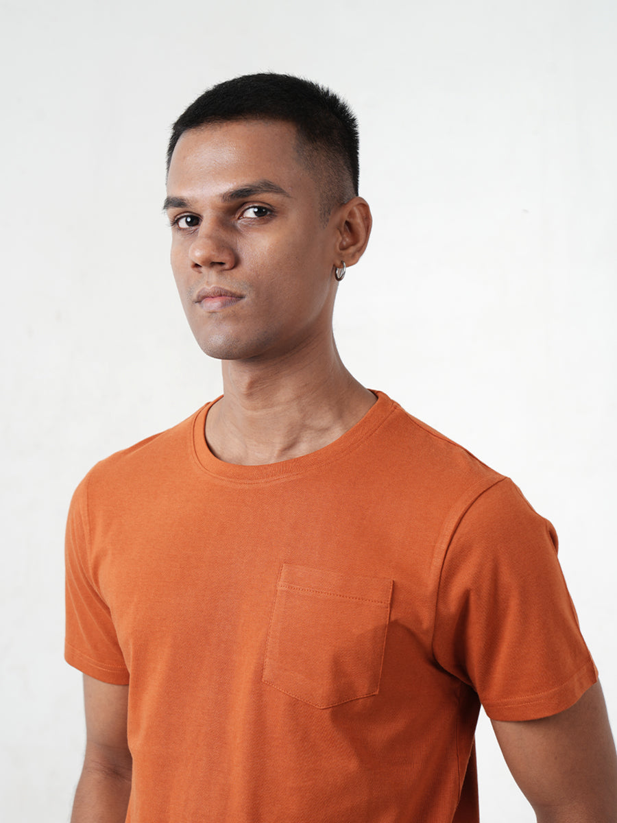 A man wearing a Monkstory bamboo cotton crew tee with a pocket, in Rusty Orange.