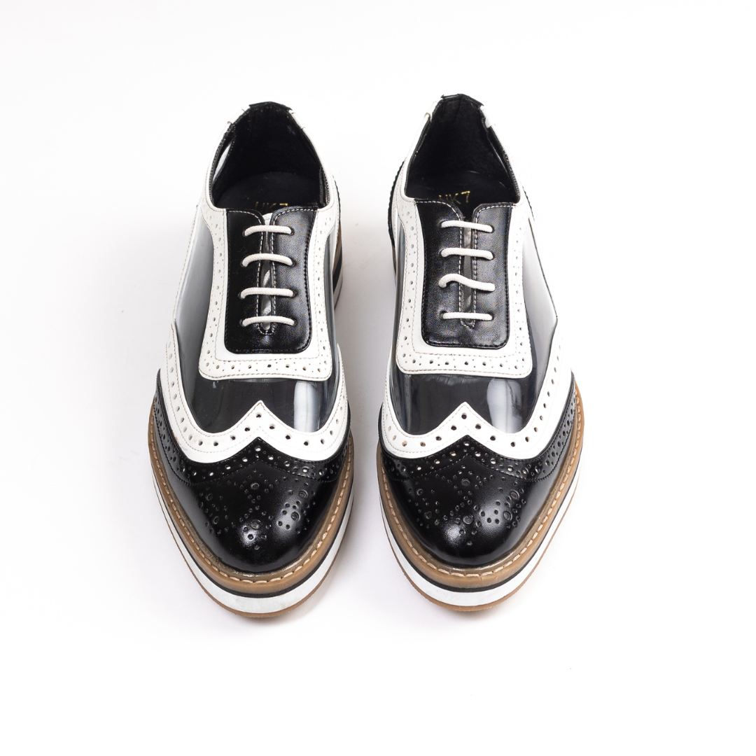 A black Trance Transparent Brogues shoe on a white background, featuring a lace-design lining for added style.