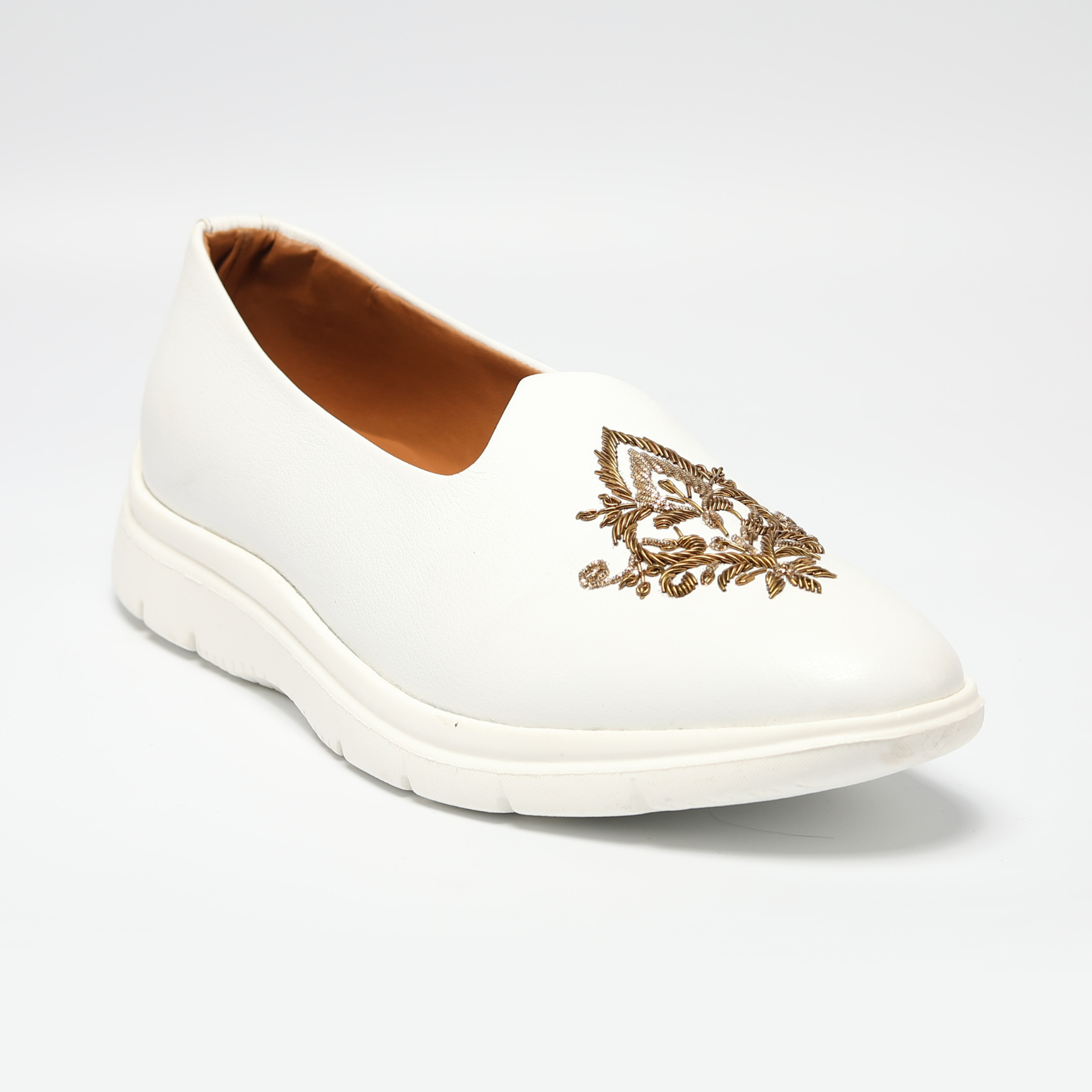 A white slip-on ReMx Mojari shoe with a gold embroidered design from Monkstory.