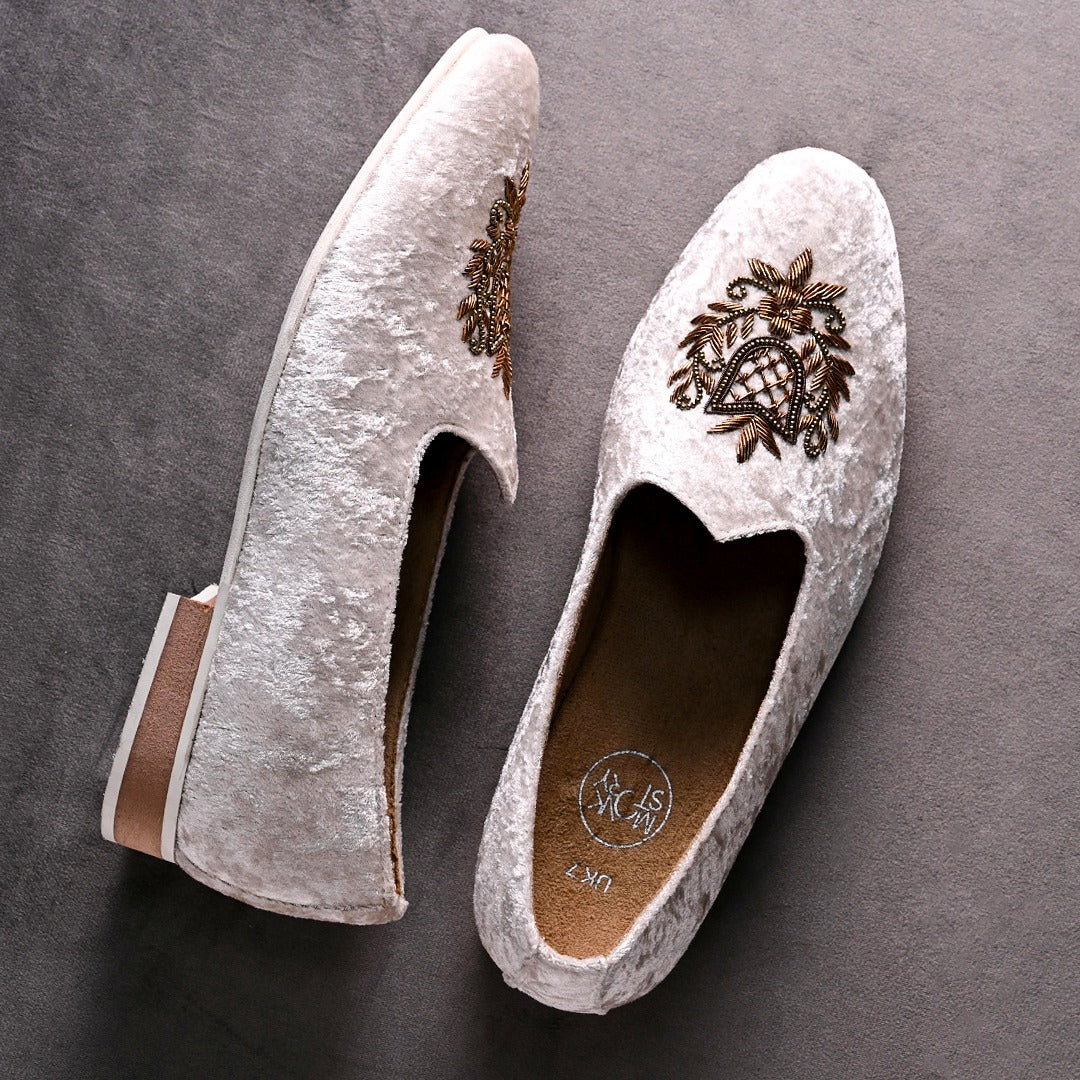 A pair of timeless white Opulenza Embroidered Mojri slippers with hand-embroidered gold motifs by monkstory.