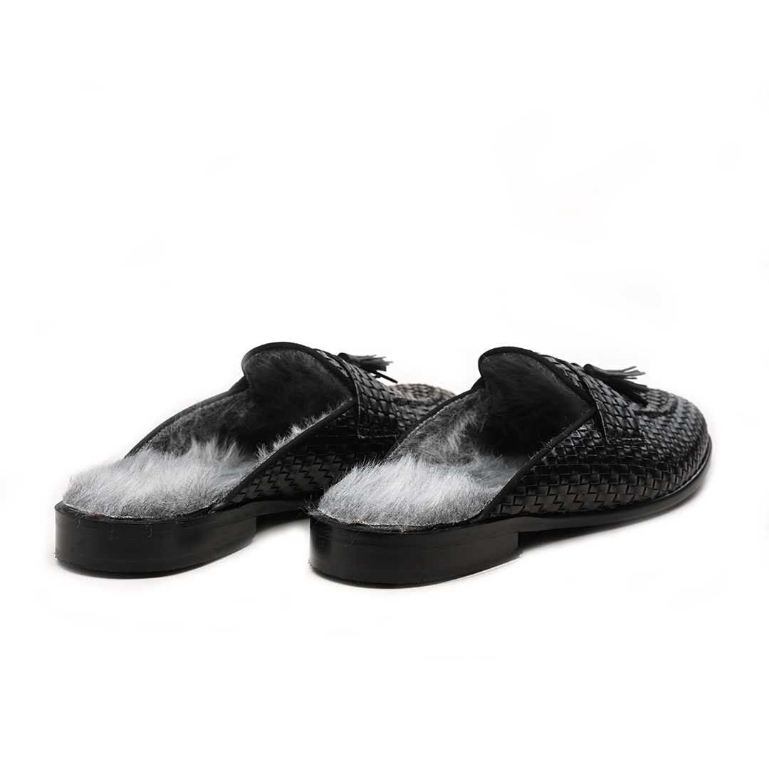 A black woven slipper with a fur tassel, featuring slip-on style and faux-fur insoles. 

Sentence: The monkstory Luxious Mule Shoes With Fur Insoles - Black feature slip-on style and faux-fur insoles.