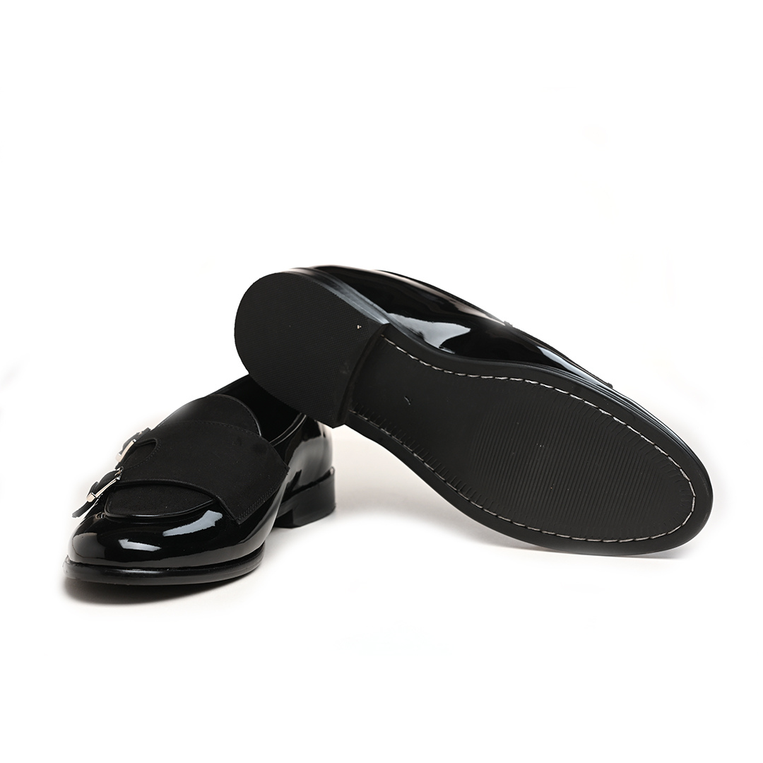 A black leather loafer with two buckles featuring posh shine.
Product: Monkstory Luxious Patent Double Monk Slip Ons - Black.