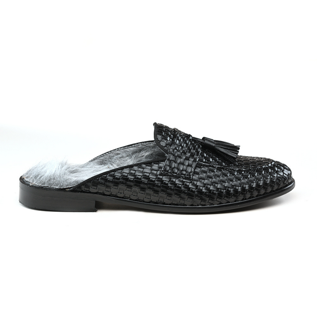 A black woven slipper with a fur tassel, featuring slip-on style and faux-fur insoles. 

Sentence: The monkstory Luxious Mule Shoes With Fur Insoles - Black feature slip-on style and faux-fur insoles.