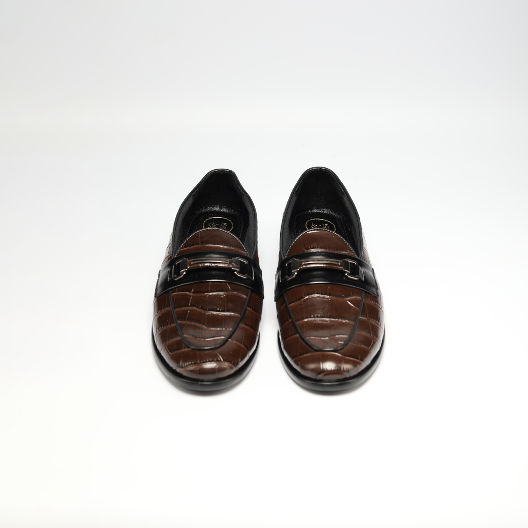 A handmade Monkstory Magnificos Classic Horsebit Slip Ons - Brown with a snake-leather look on a white background.