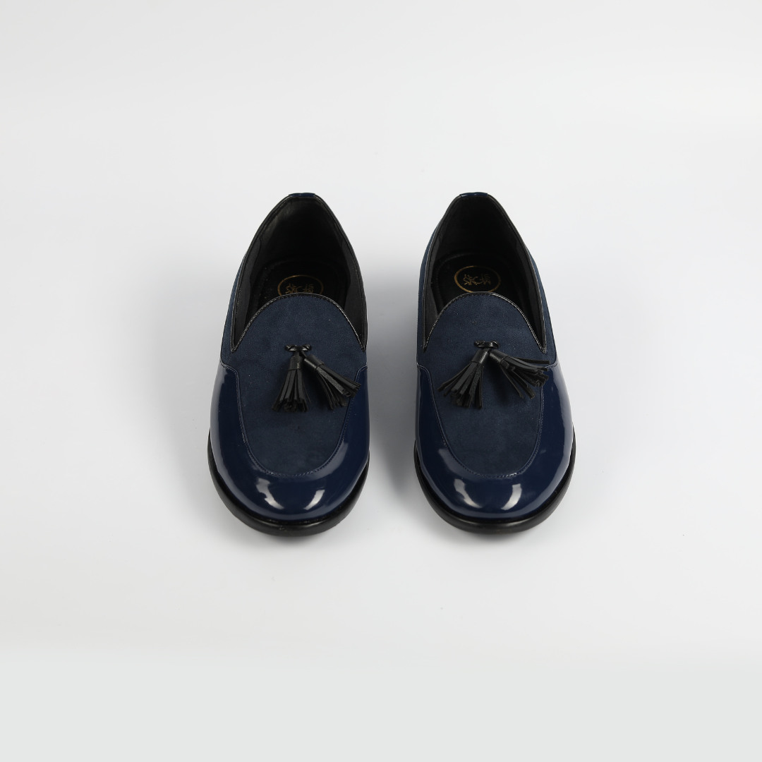 A blue loafer with a tassel made from Monkstory's Magnificos Patent With Suede Tasseled Slip Ons - Blue.