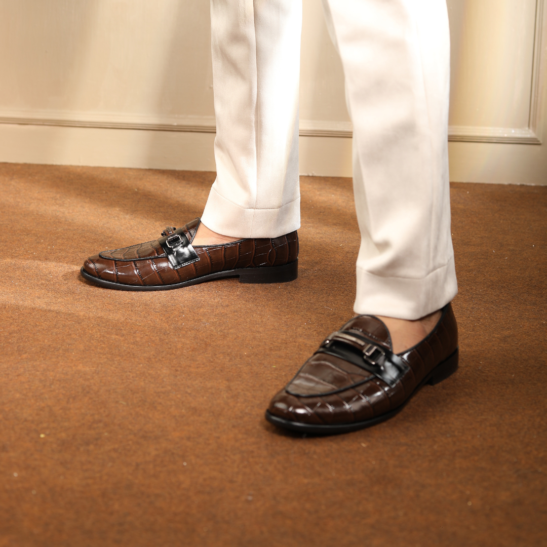 A handmade Monkstory Magnificos Classic Horsebit Slip Ons - Brown with a snake-leather look on a white background.