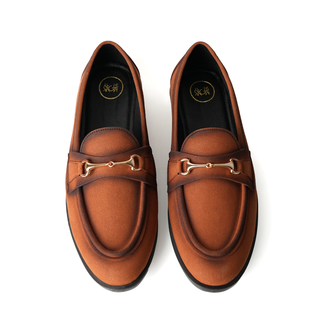 A pair of Flatform Suede Horsebit Slip Ons - Burnish Brown loafers with a gold buckle from Monkstory.