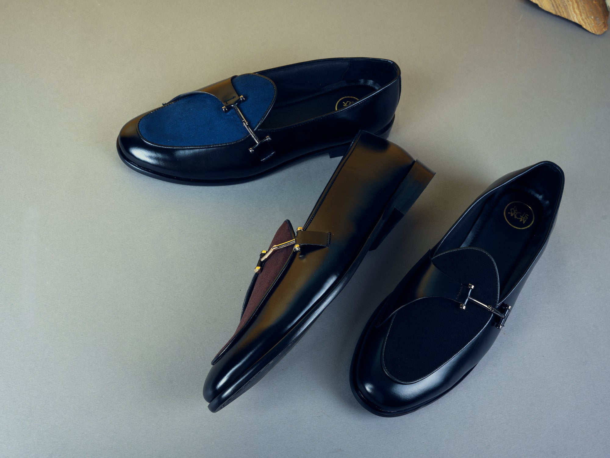 Two pairs of stylish loafers on a gray surface.