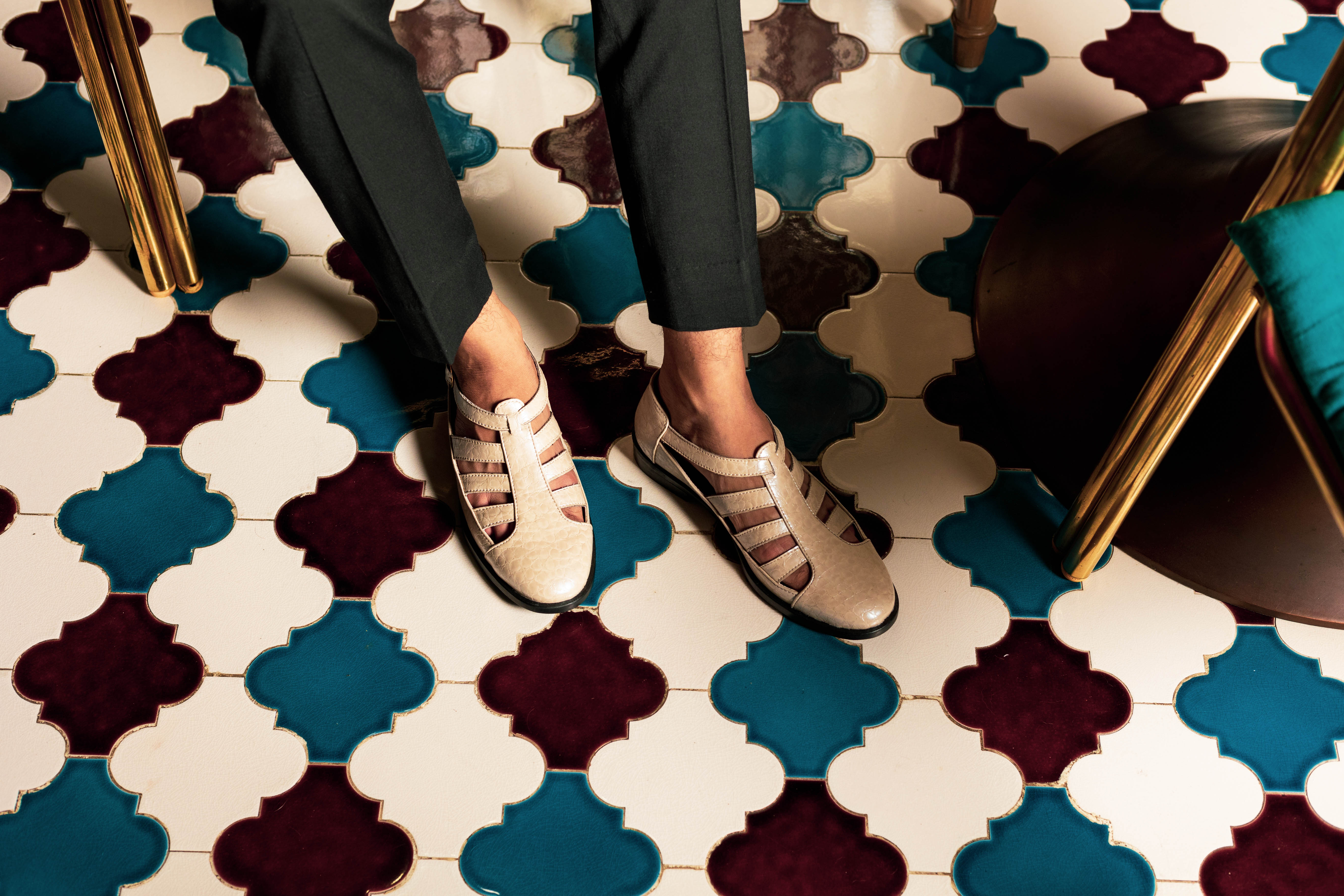 A person's feet on a colorful tiled floor.
