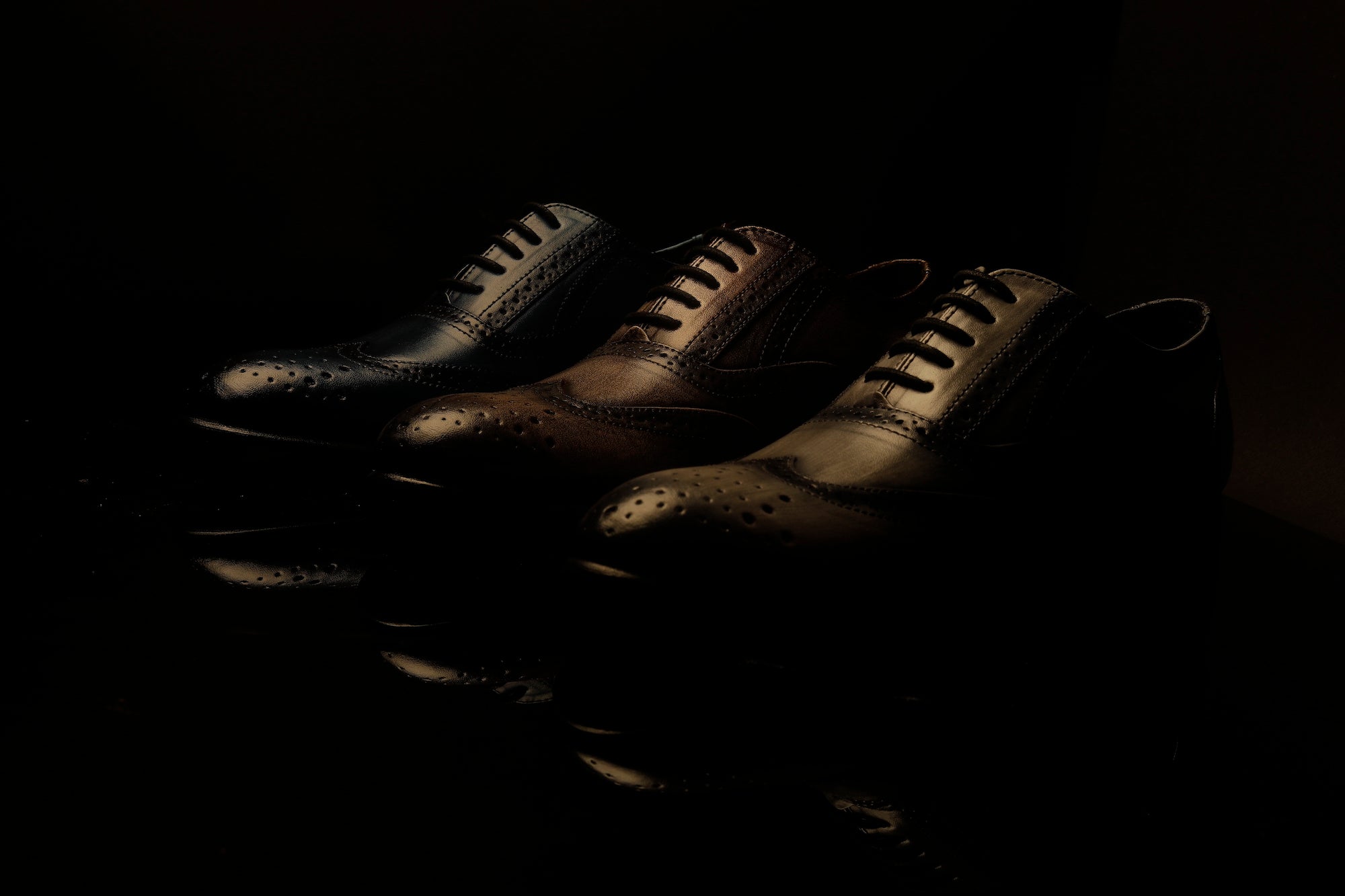 A pair of black shoes on a black background.