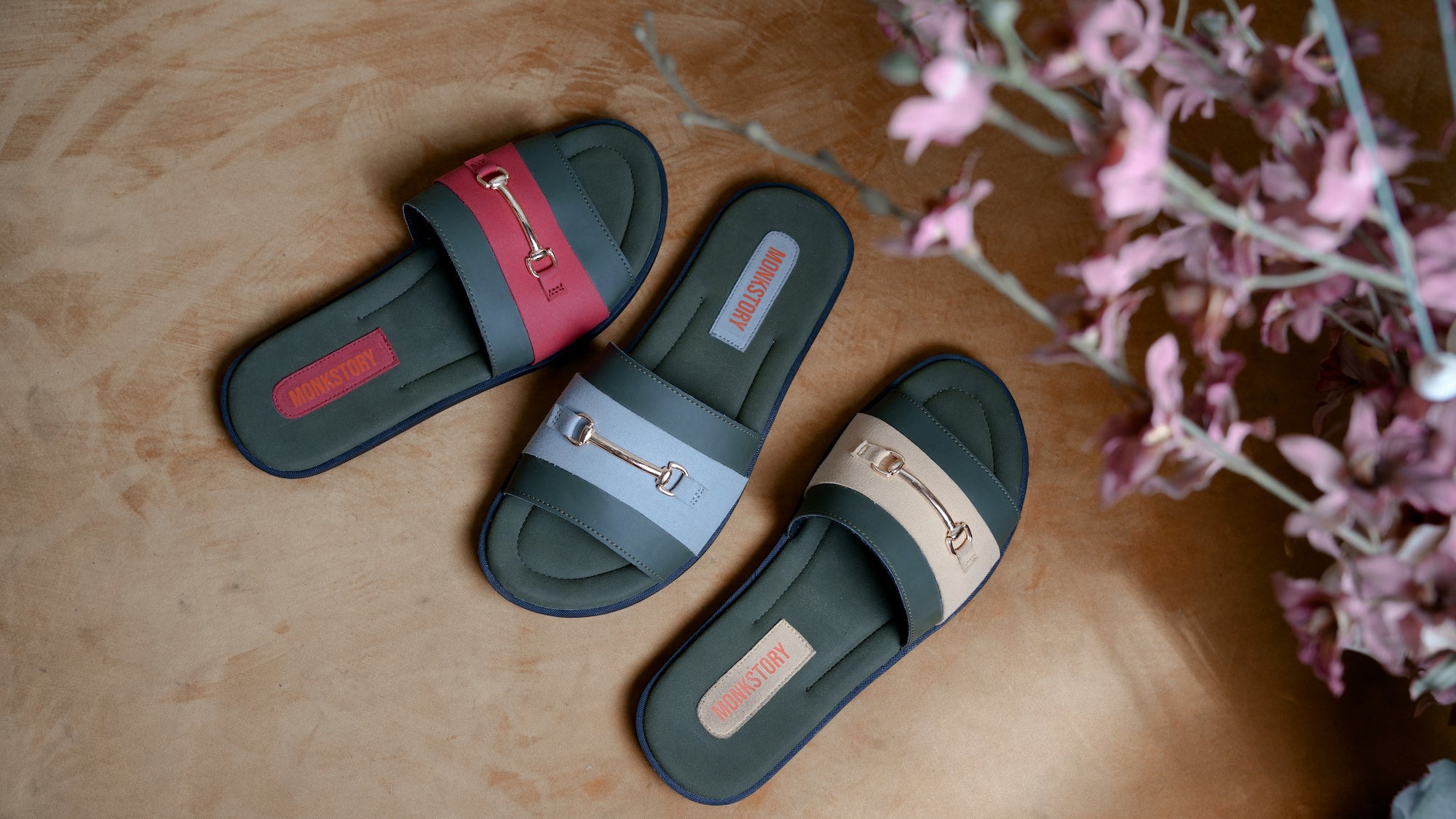 A pair of slide sandals with a flower in the background.