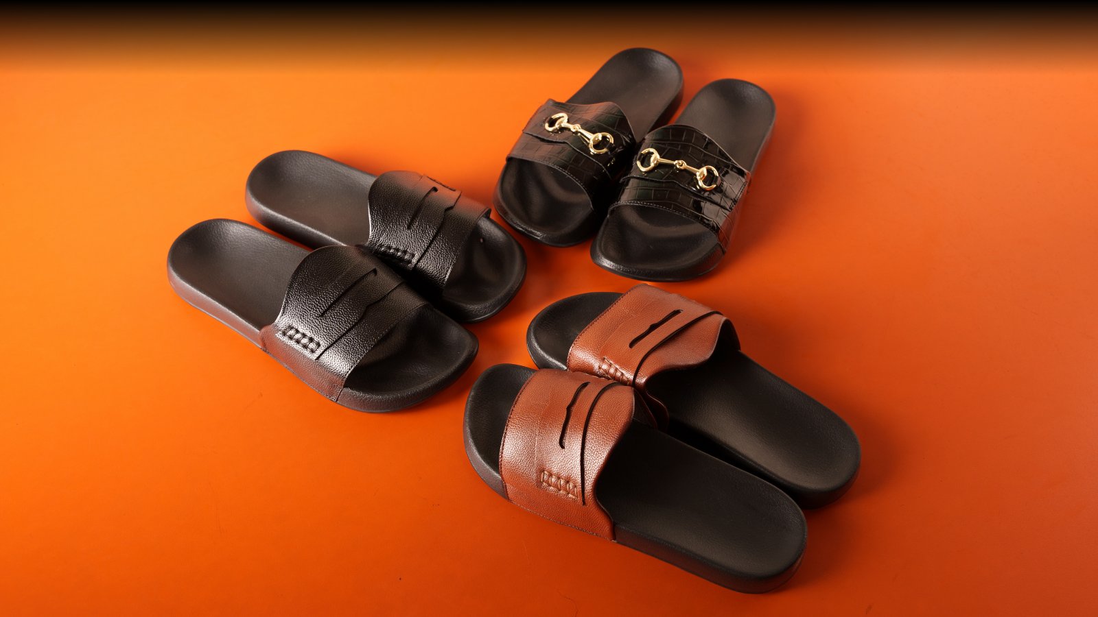 A pair of slide sandals with a flower in the background.