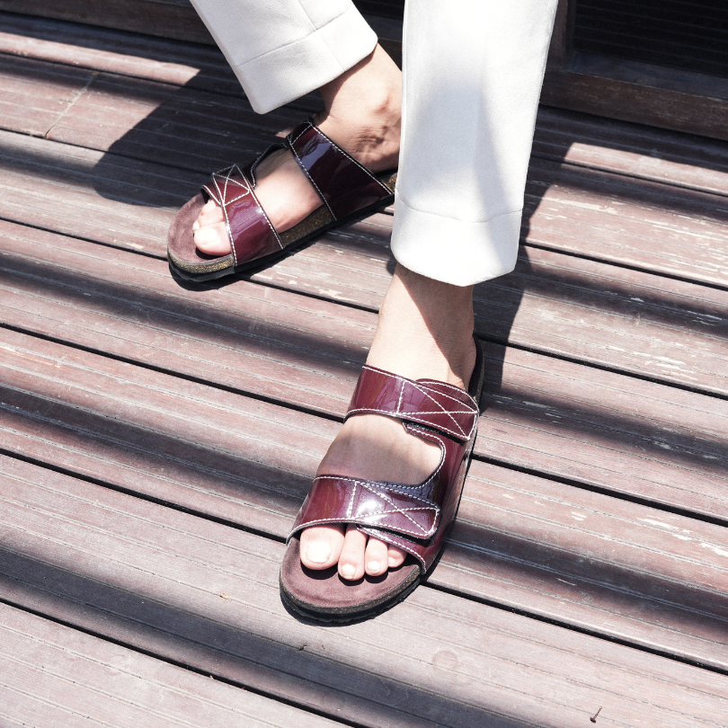 A pair of glossy brown Monkstory sandals with cork dual-straps on a white background.