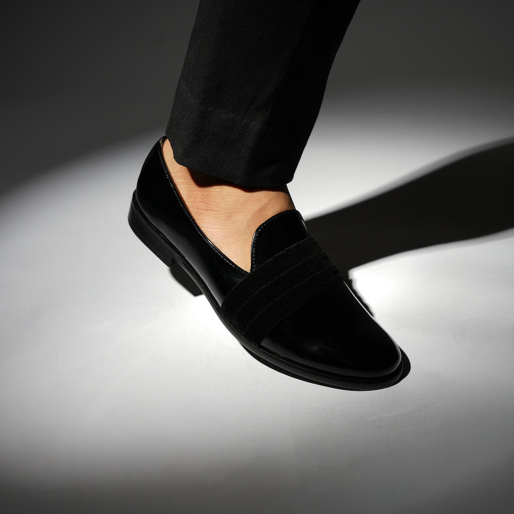 A black Tuxedo Slip-on with a patent leather finish and a bow on the side, by Monkstory.