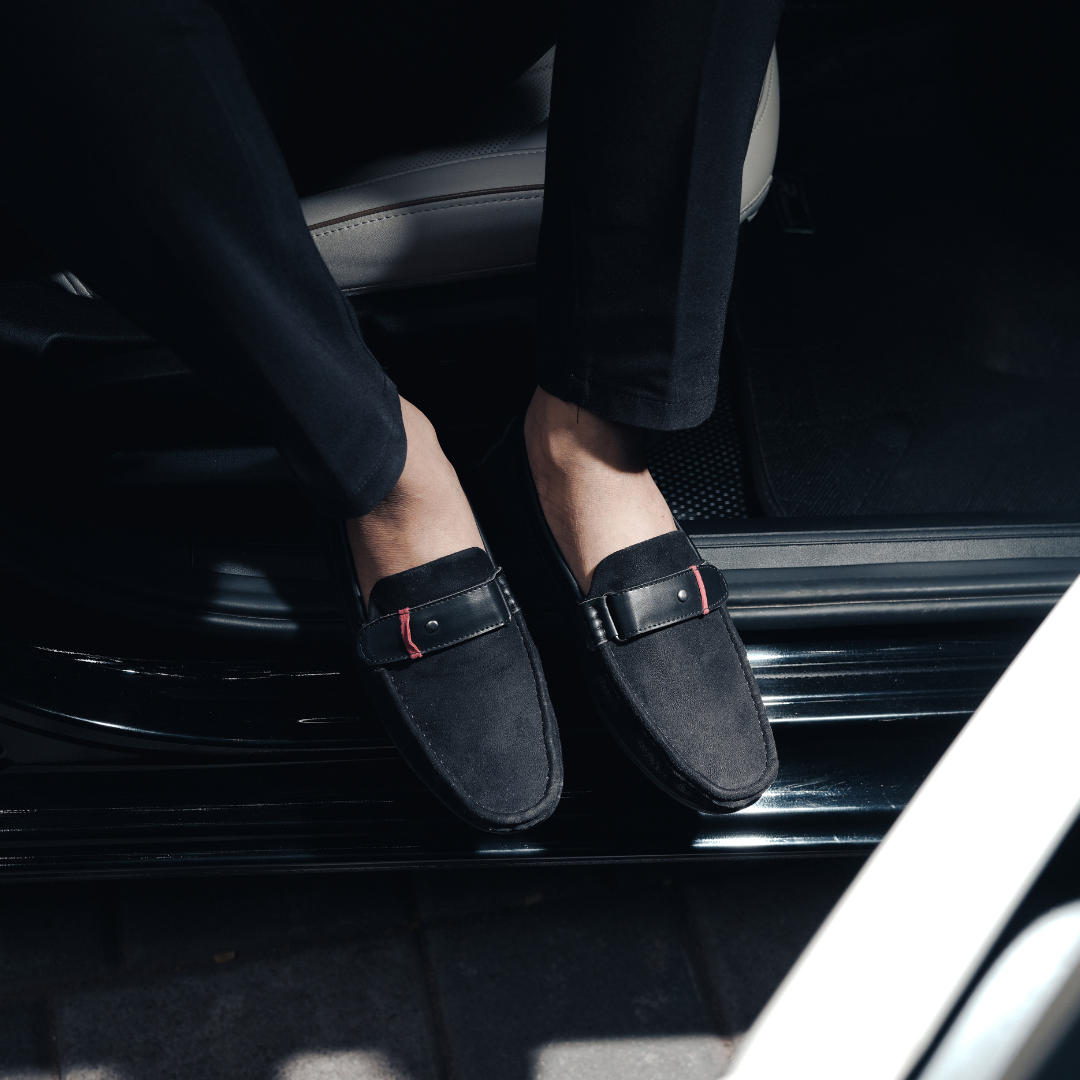 A comfortable Monkstory black loafer with a red stripe, perfect for driving.