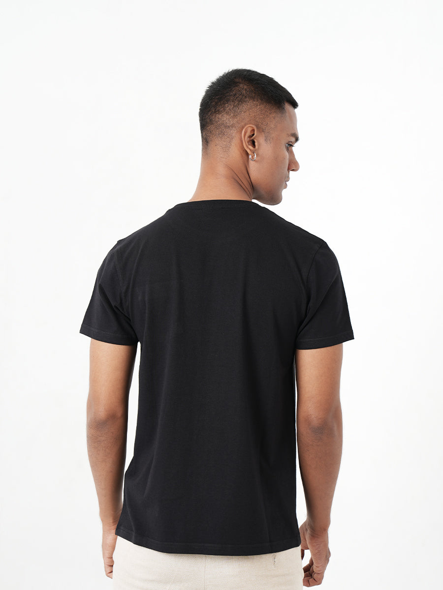 A man wearing a black t-shirt with a pocket, showcasing the Monkstory Bamboo Cotton Crew Tee - Classic Black for unmatched softness.