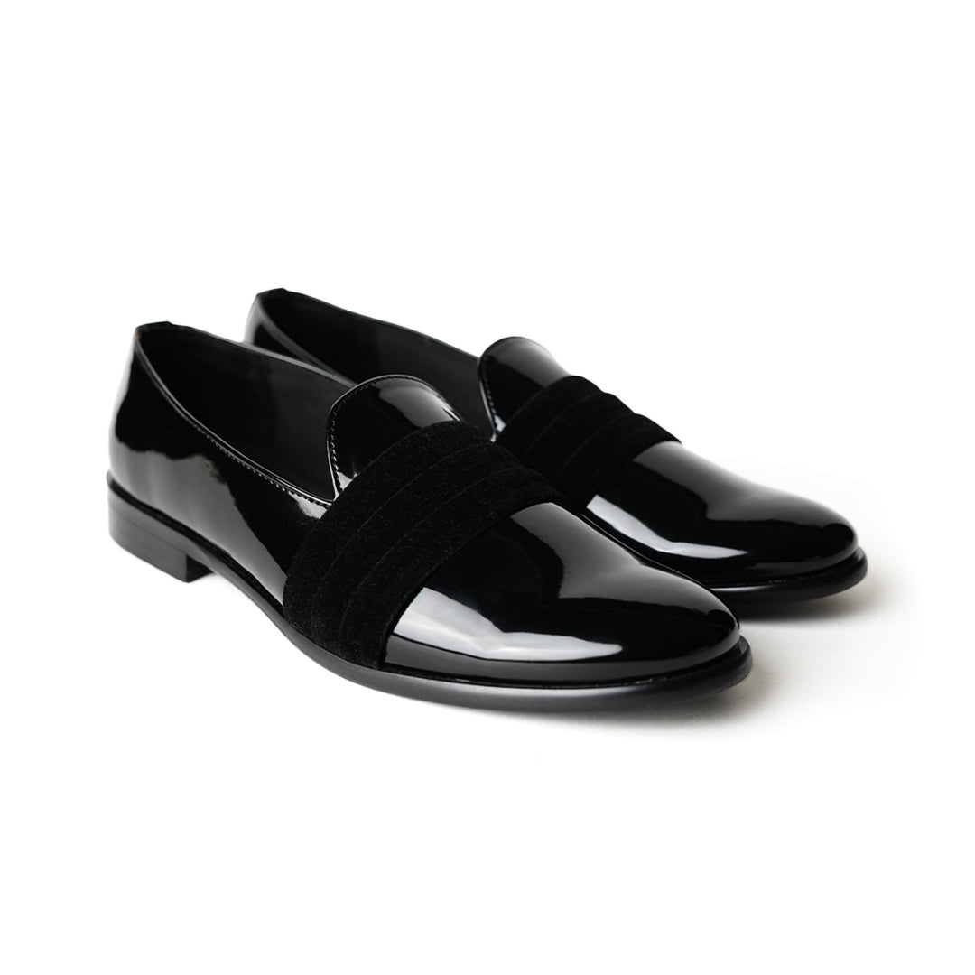 A black Tuxedo Slip-on with a patent leather finish and a bow on the side, by Monkstory.