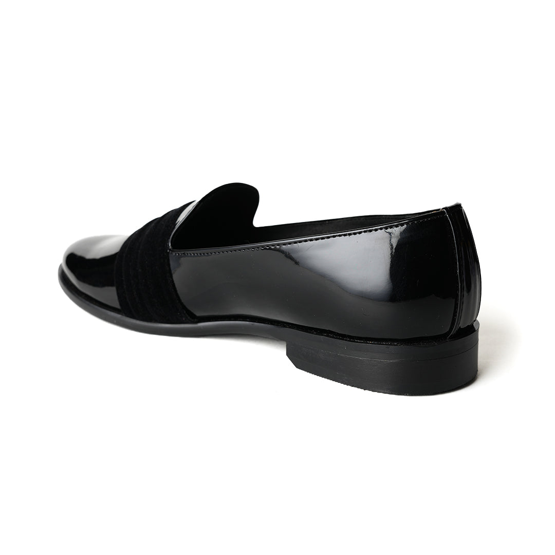 A black Tuxedo Slip-on with a patent leather finish and a bow on the side, by Monkstory.