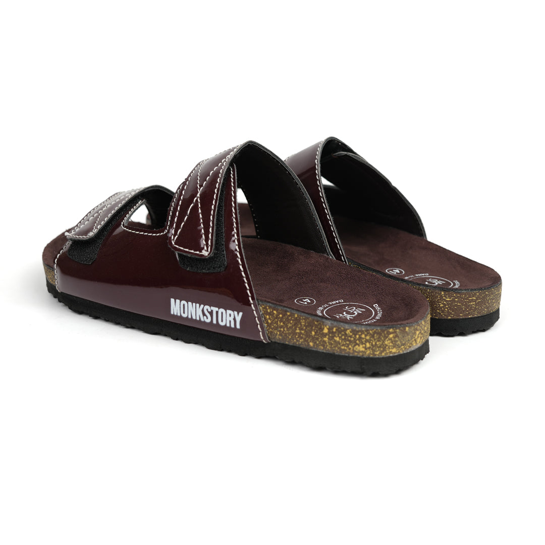 A pair of glossy brown Monkstory sandals with cork dual-straps on a white background.
