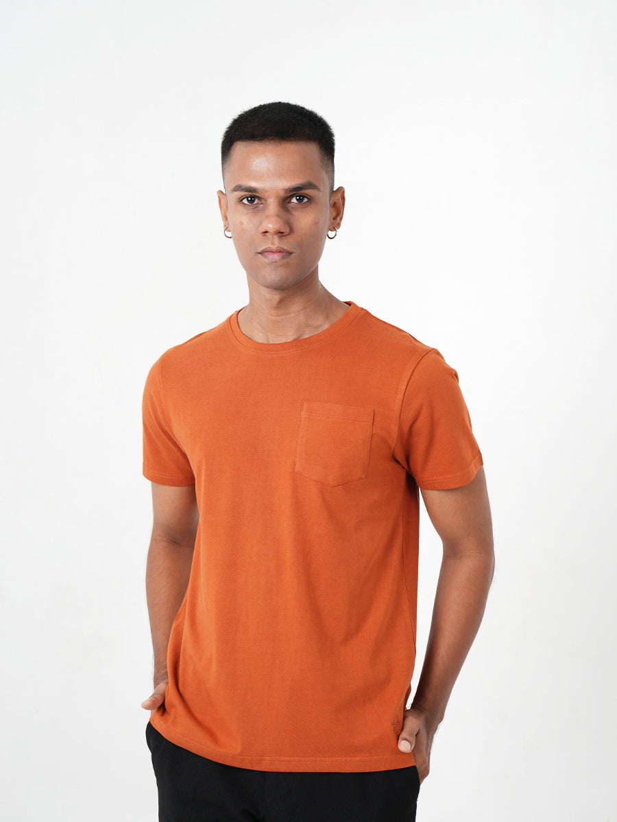 A man wearing a Monkstory bamboo cotton crew tee with a pocket, in Rusty Orange.