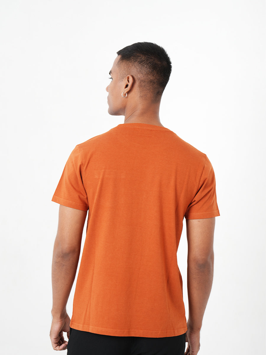 A man wearing a Monkstory bamboo cotton crew tee with a pocket, in Rusty Orange.