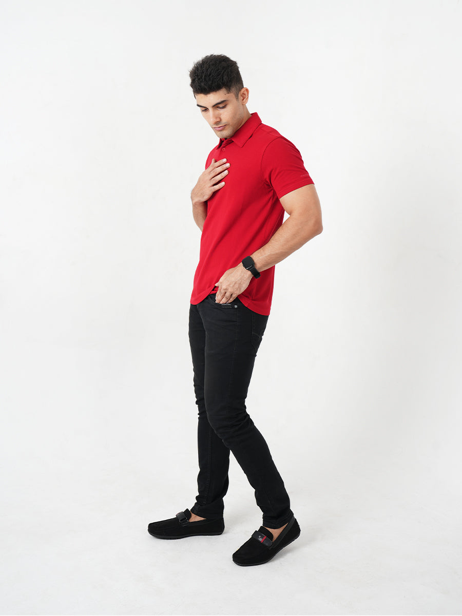 A man in a Monkstory Bamboo Cotton Polo Tee - Fiery Red adjusting his watch with comfort.