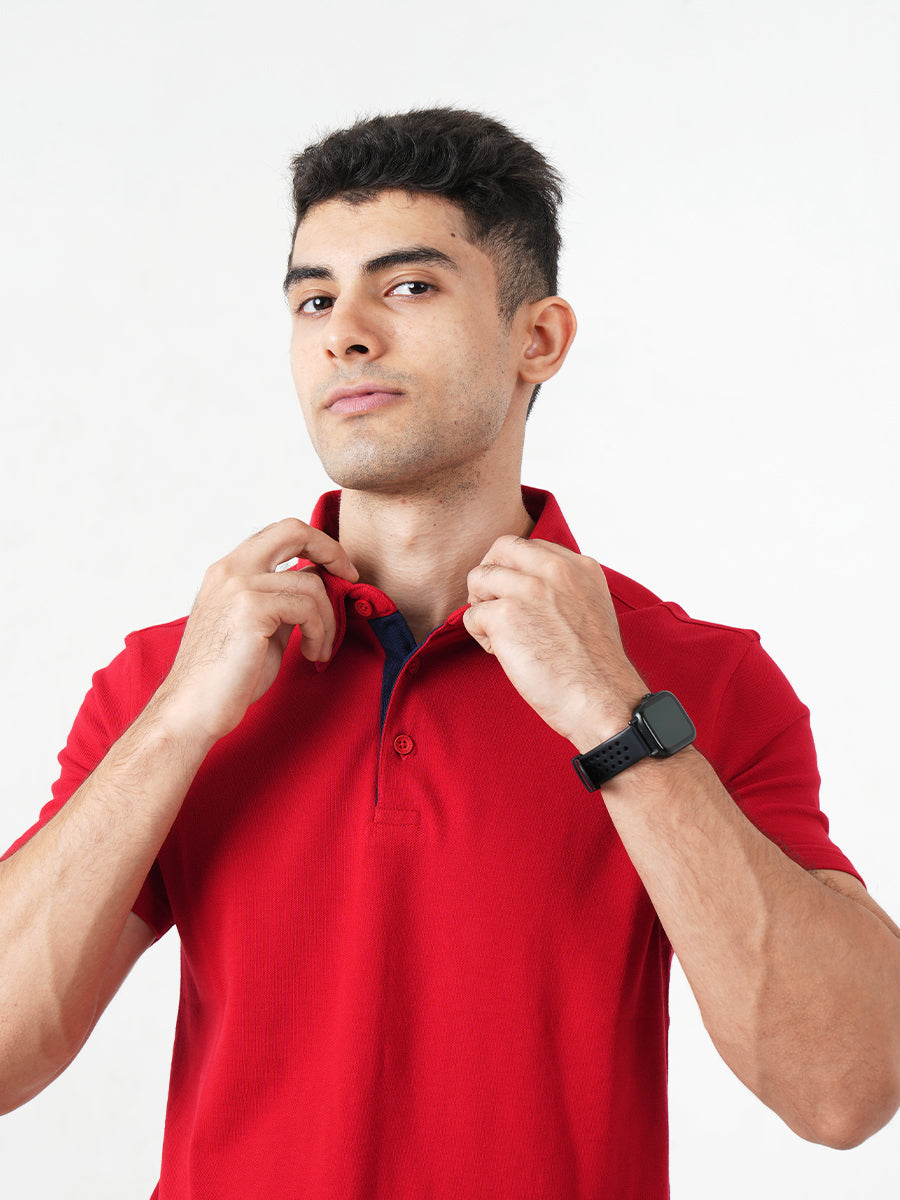 A man in a Monkstory Bamboo Cotton Polo Tee - Fiery Red adjusting his watch with comfort.