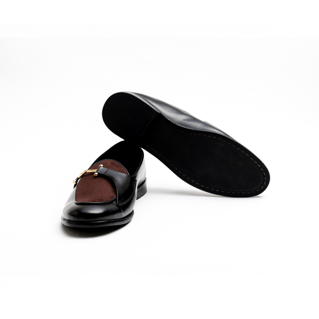 An Eclecta Side Buckle Slip Ons loafer in brown and black vegan leather with a gold buckle. (Monkstory)