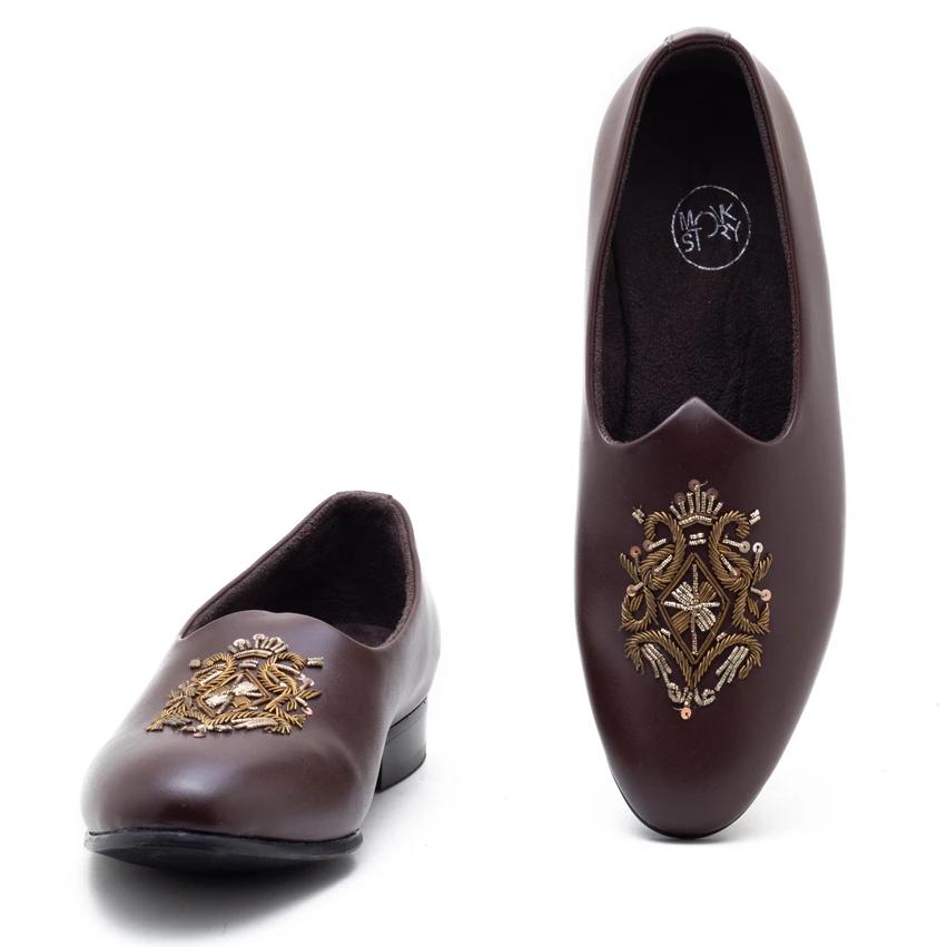A pair of Monkstory Magenta Mojri shoes with brown embroidered designs.