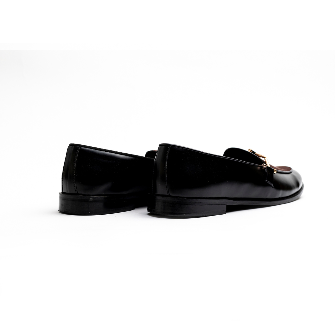 An Eclecta Side Buckle Slip Ons loafer in brown and black vegan leather with a gold buckle. (Monkstory)