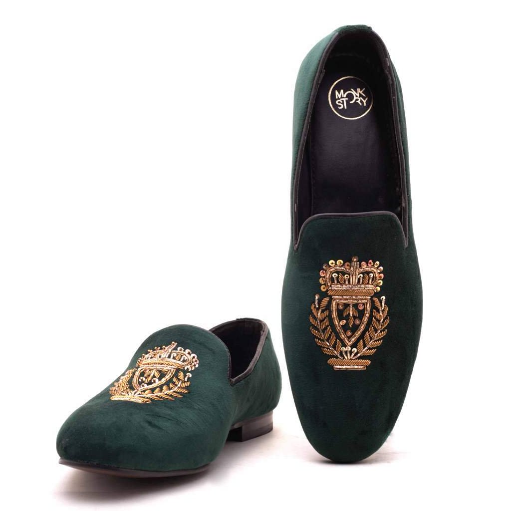 A pair of Ross Green Velvet Slip Ons with a gold crest, making them Monkstory designer shoes.