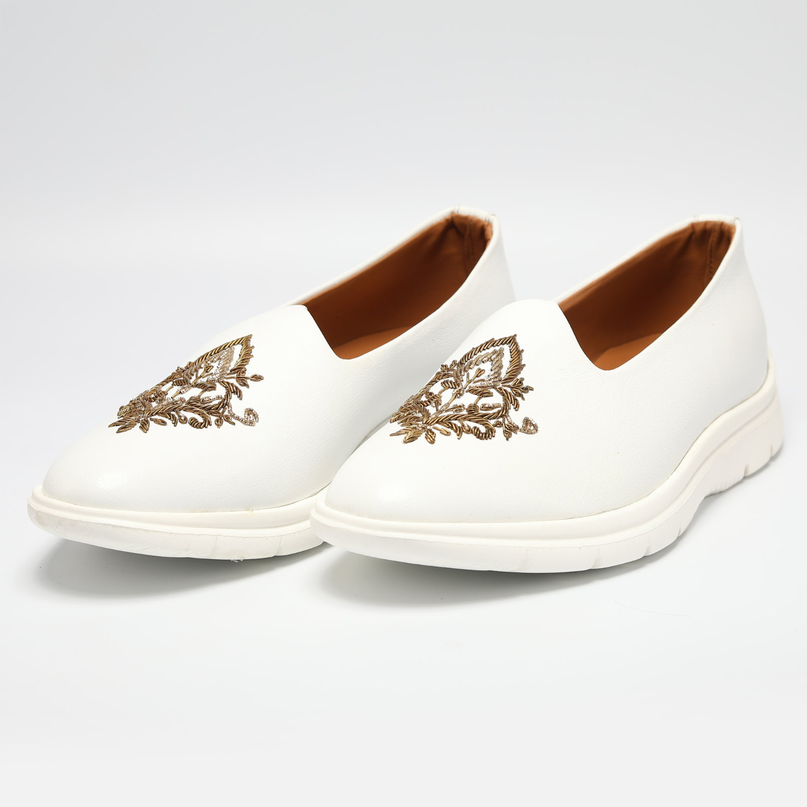 A white slip-on ReMx Mojari shoe with a gold embroidered design from Monkstory.