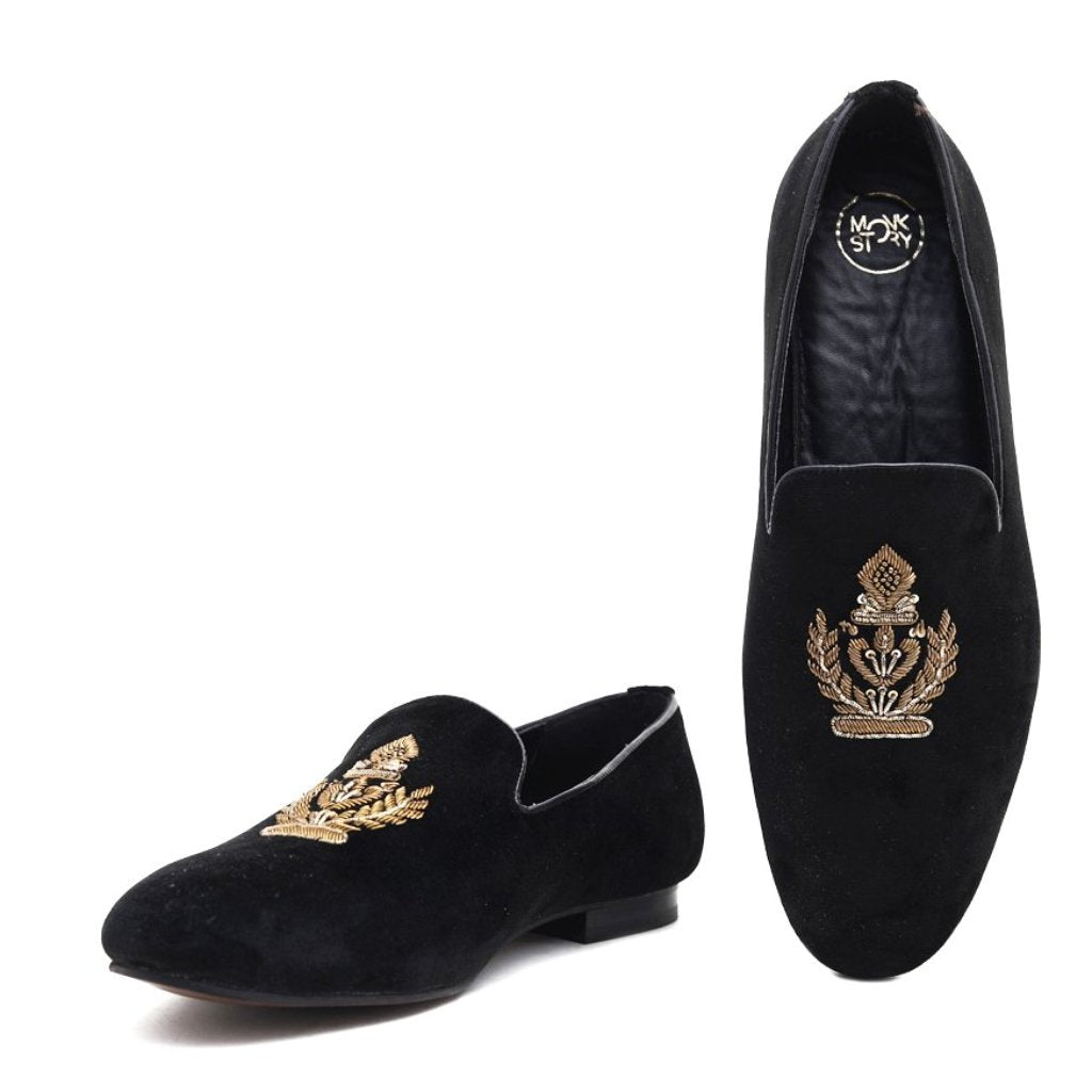 A pair of Ross Black Velvet Slip Ons with a gold crest, perfect for those seeking Monkstory designer shoes.