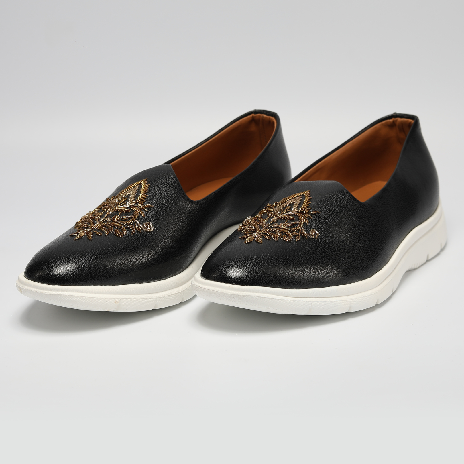 A black leather slip on shoe with gold embroidery, perfect for ethnic wear.