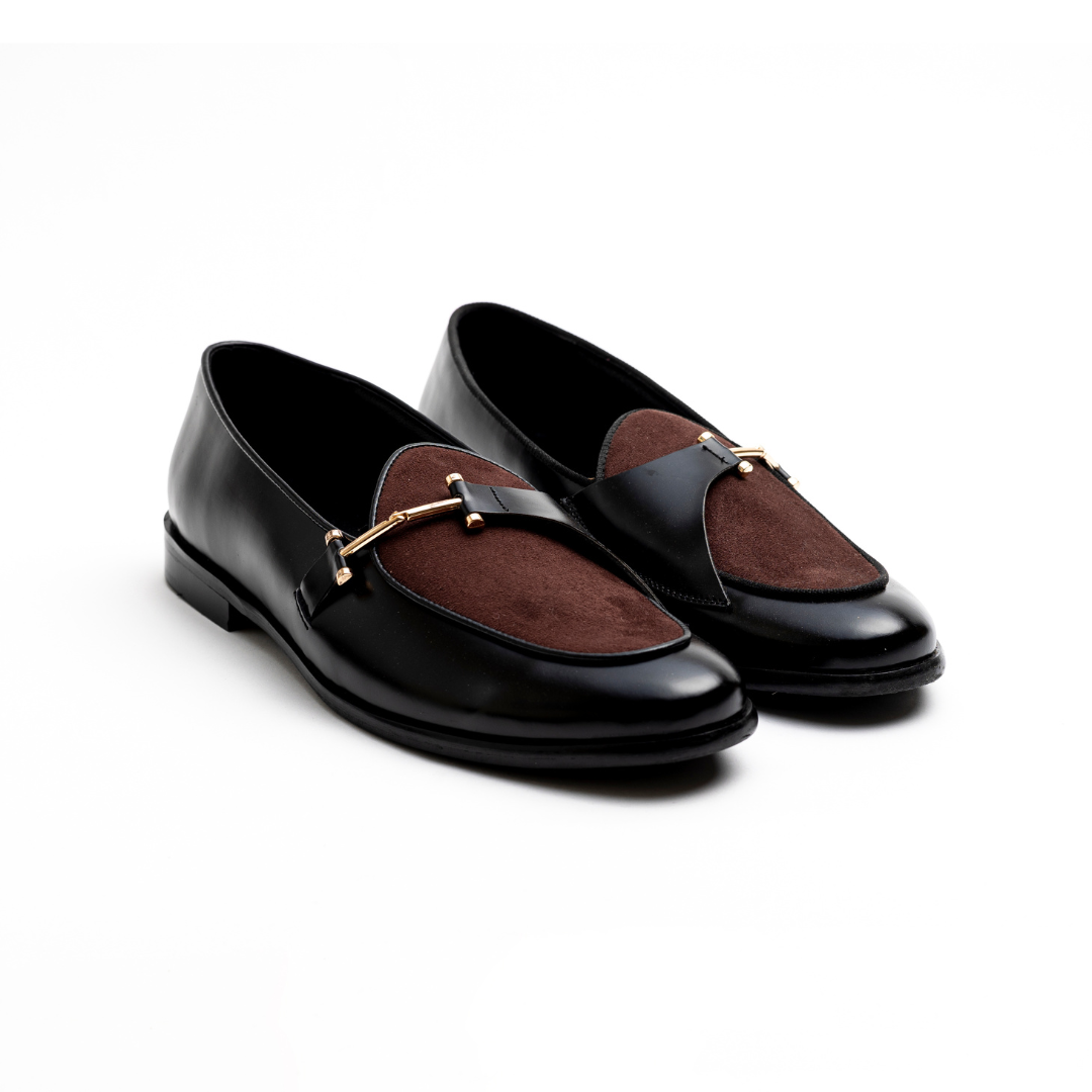 An Eclecta Side Buckle Slip Ons loafer in brown and black vegan leather with a gold buckle. (Monkstory)