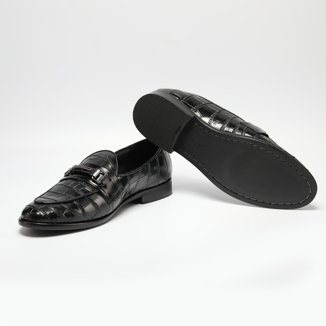 A versatile black crocodile skin loafer, the Magnificos Classic Horsebit Slip Ons by Monkstory, with a snake-leather look on a white background.