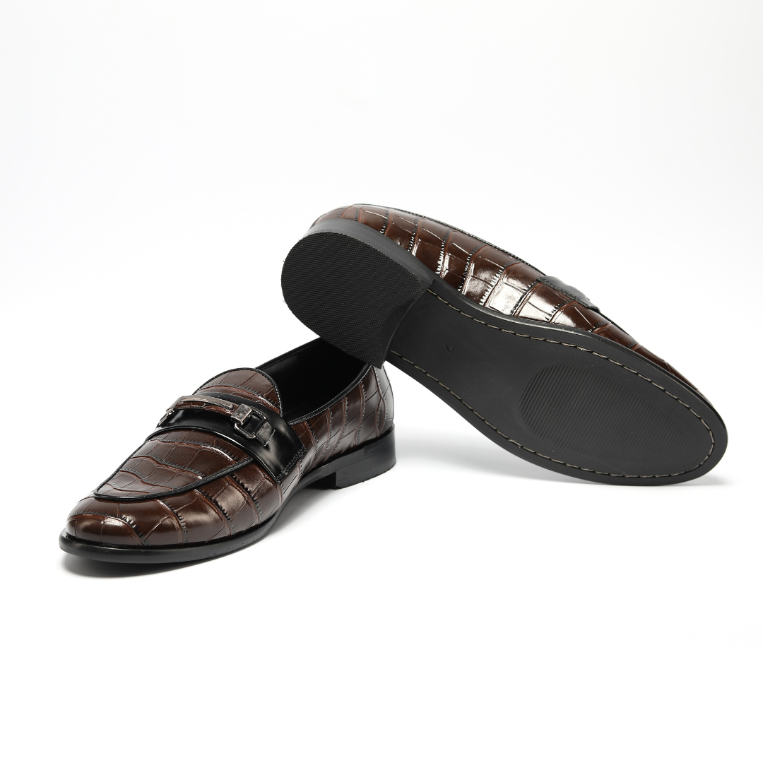 A handmade Monkstory Magnificos Classic Horsebit Slip Ons - Brown with a snake-leather look on a white background.