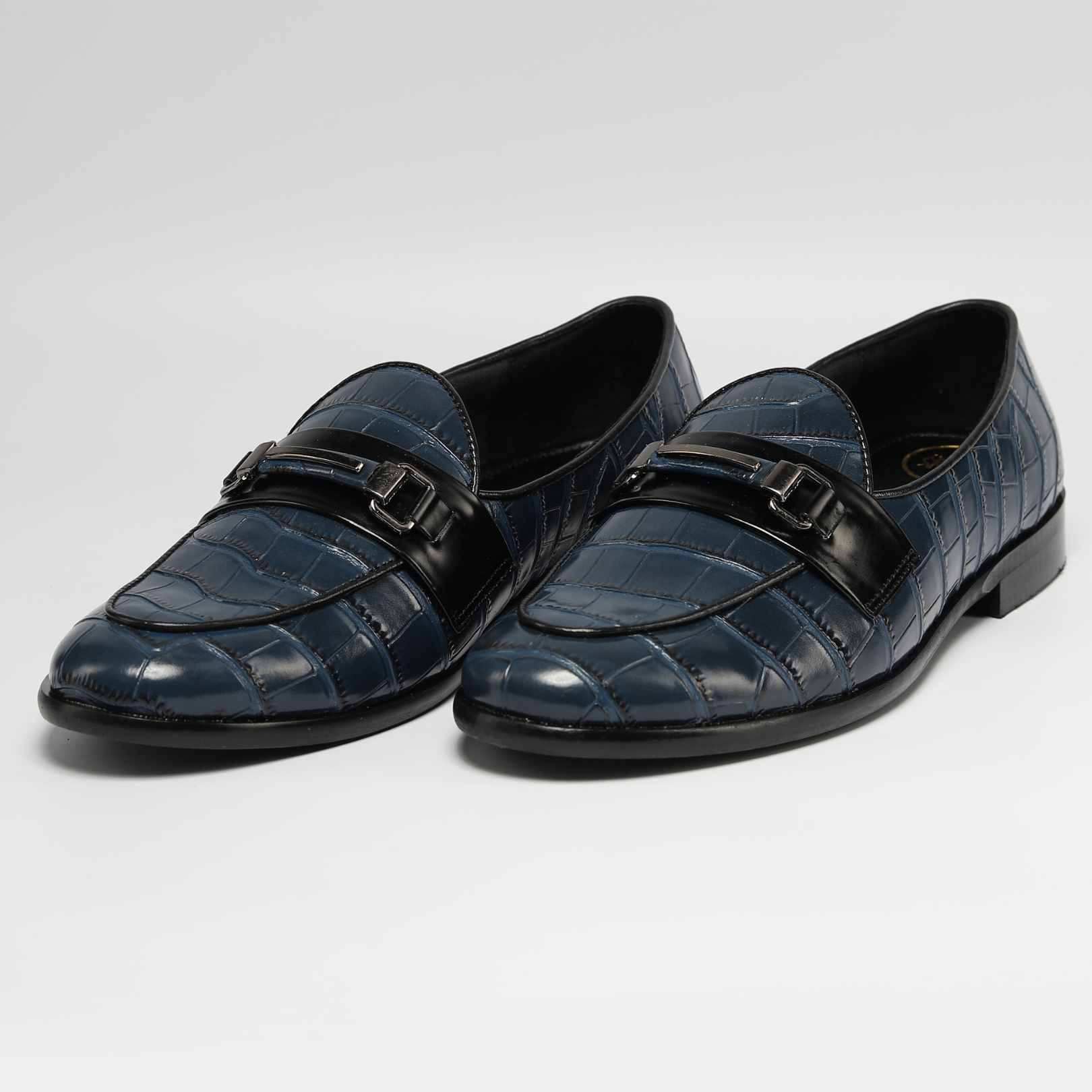 A versatile blue Magnificos Classic Horsebit Slip Ons crocodile print loafer with a black buckle, perfect for those who prefer vegan shoes. (Brand Name: Monkstory)