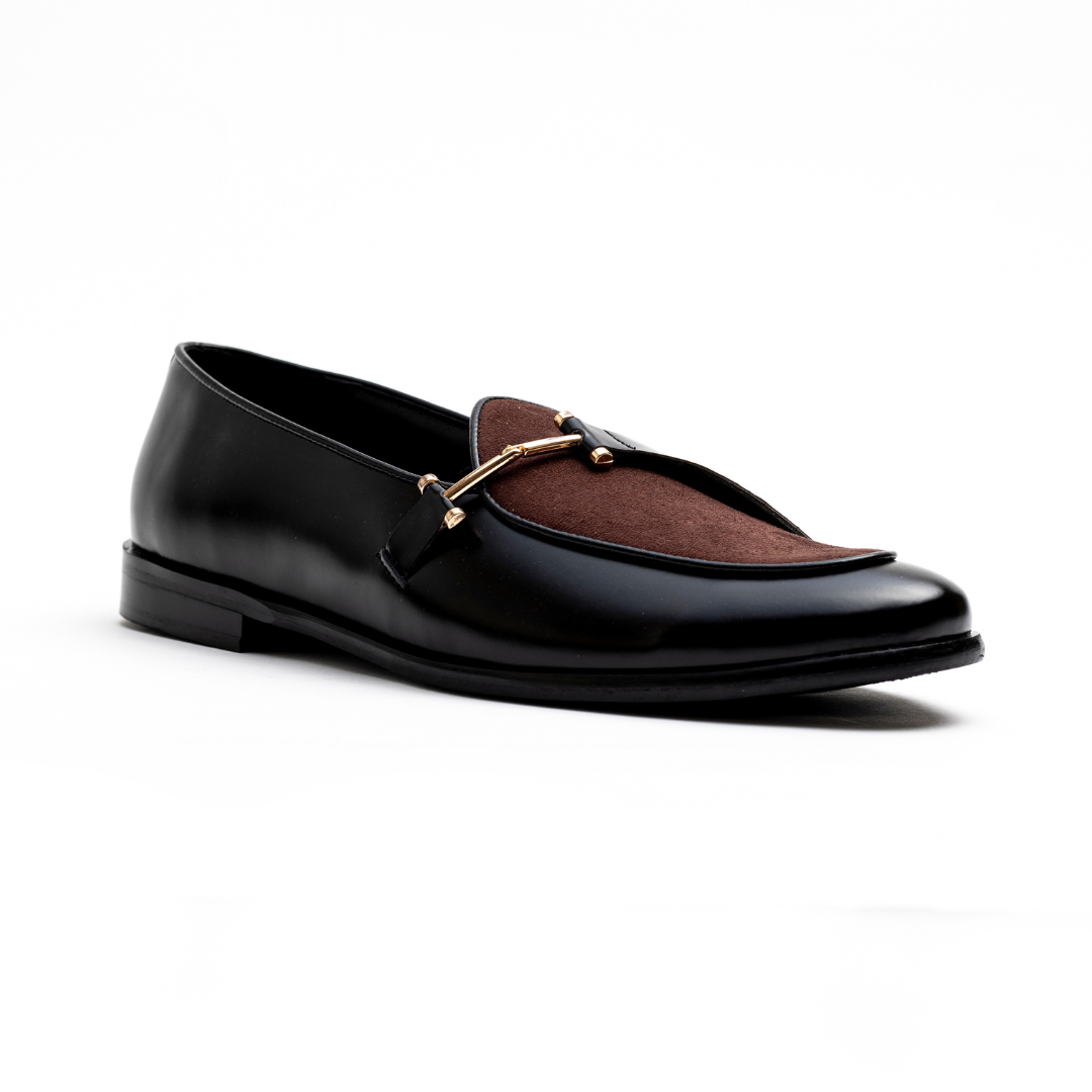 An Eclecta Side Buckle Slip Ons loafer in brown and black vegan leather with a gold buckle. (Monkstory)