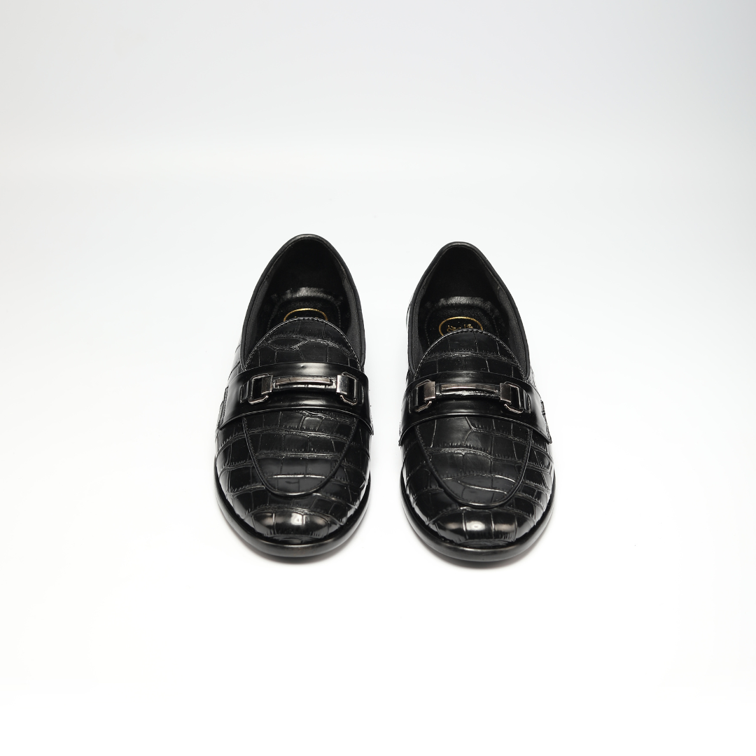 A versatile black crocodile skin loafer, the Magnificos Classic Horsebit Slip Ons by Monkstory, with a snake-leather look on a white background.