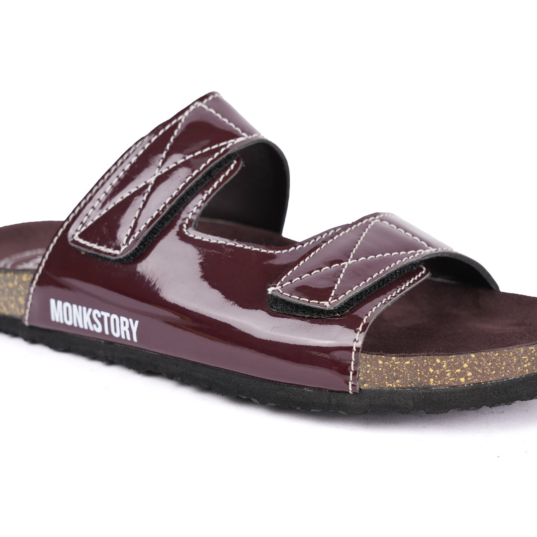 A pair of glossy brown Monkstory sandals with cork dual-straps on a white background.