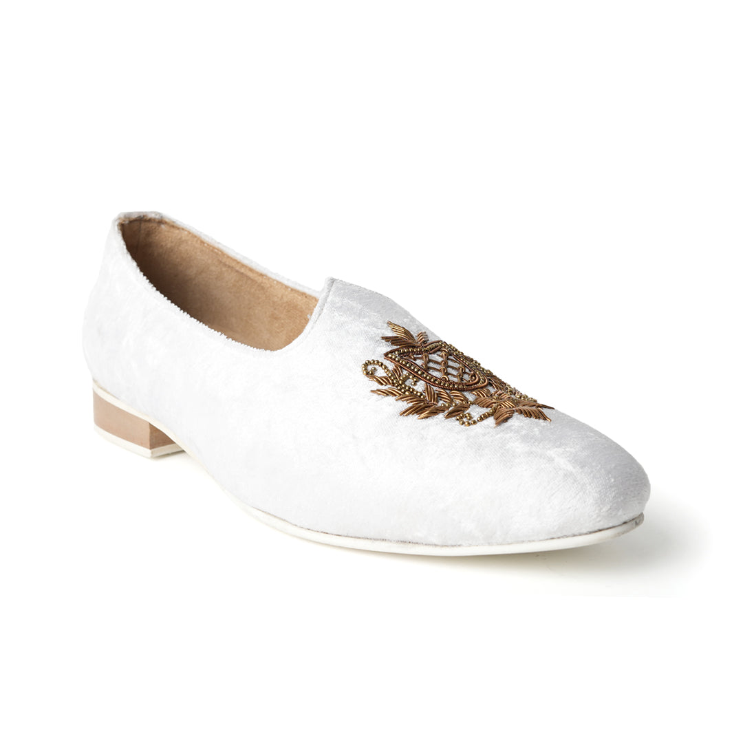 A pair of timeless white Opulenza Embroidered Mojri slippers with hand-embroidered gold motifs by monkstory.