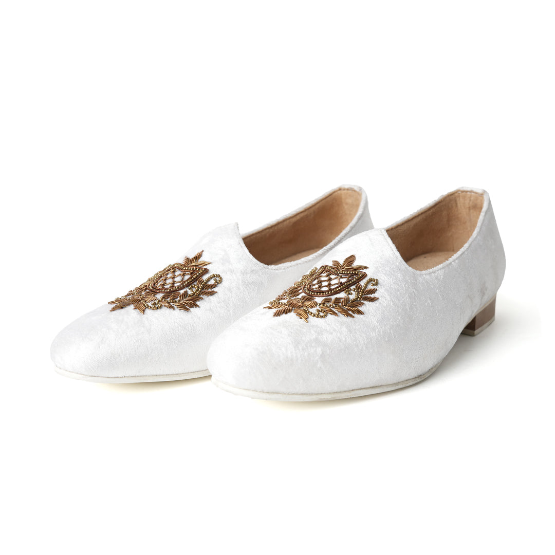 A pair of timeless white Opulenza Embroidered Mojri slippers with hand-embroidered gold motifs by monkstory.
