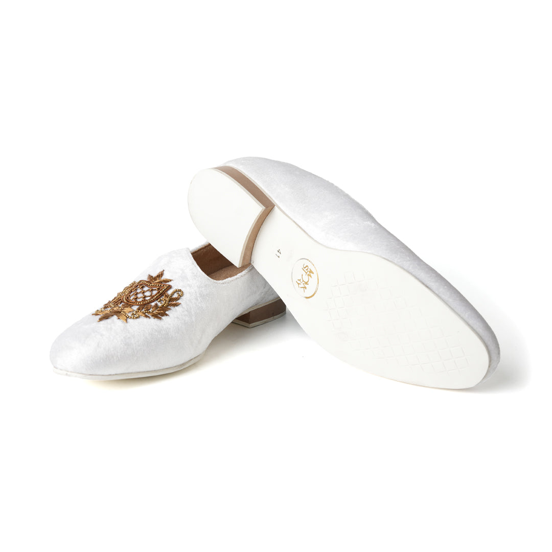 A pair of timeless white Opulenza Embroidered Mojri slippers with hand-embroidered gold motifs by monkstory.